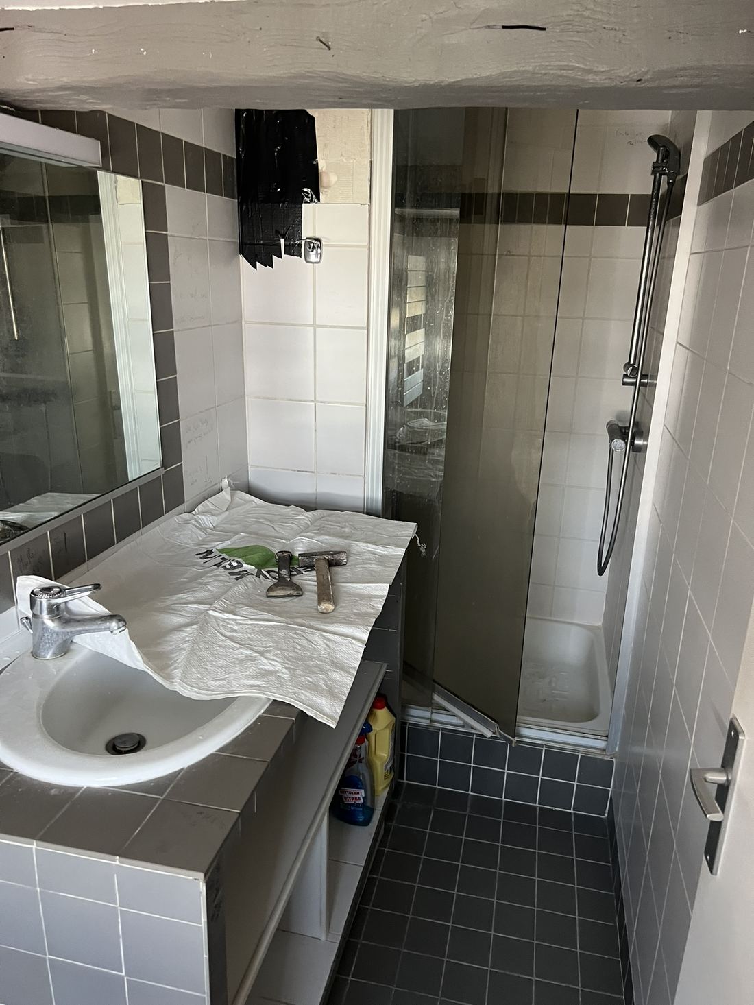 Avant : carrelage gris daté, douche vieillissante